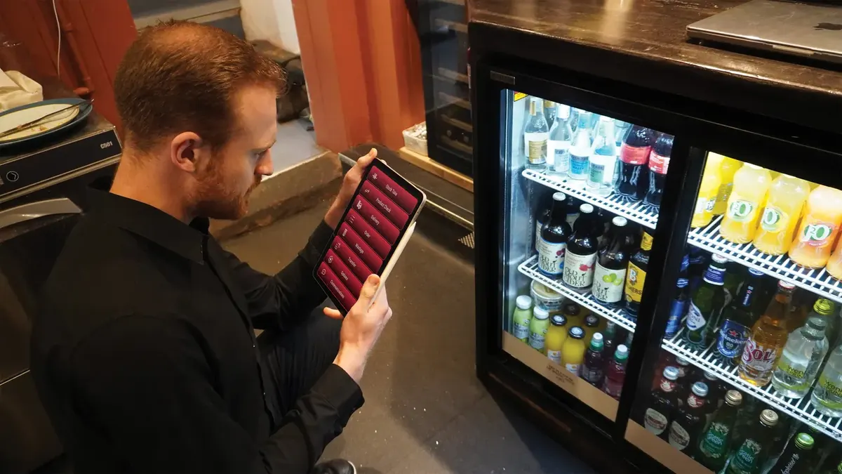 Bar manager checking stock on a handheld EPOS