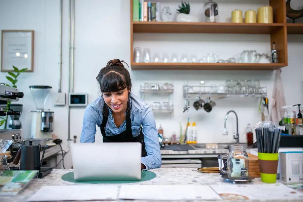Café owner working on a website on a laptop at the counter